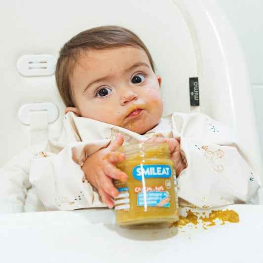 bebe comiendo tarrito de arroz integral con salmón y guisantes